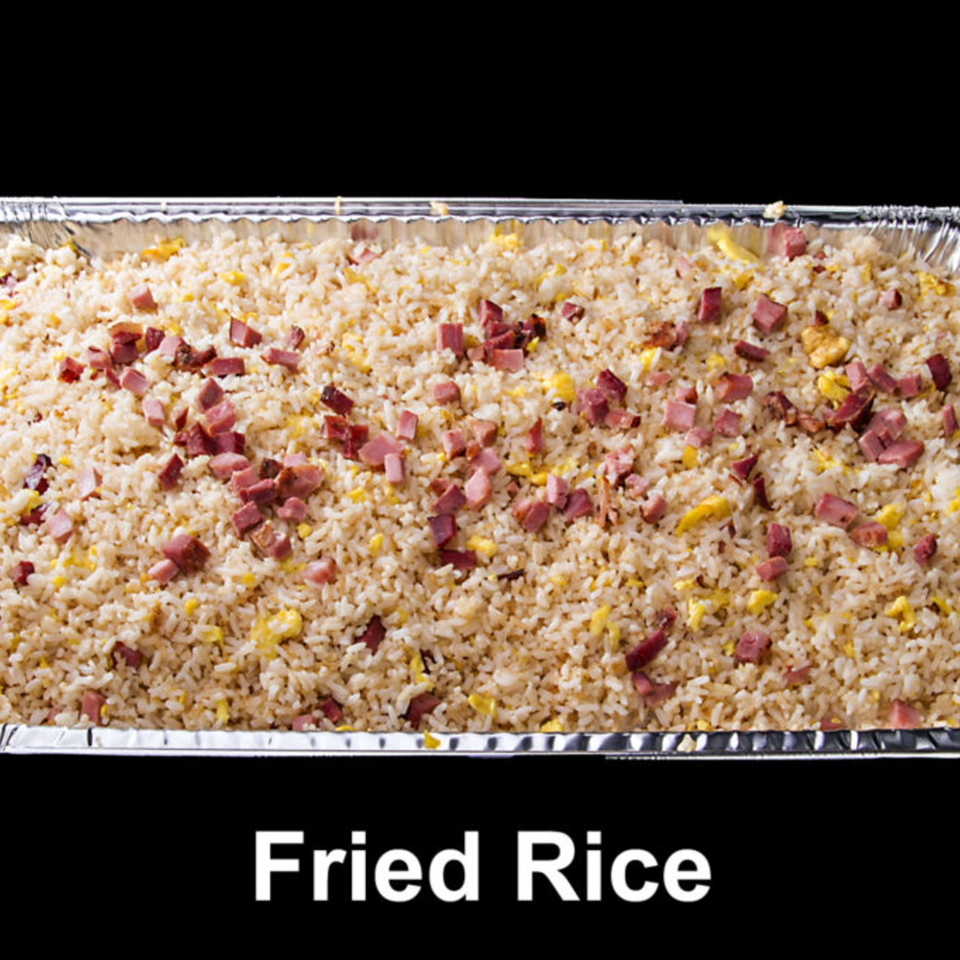 A large aluminum tray filled with fried rice, scrambled eggs, and diced ham.