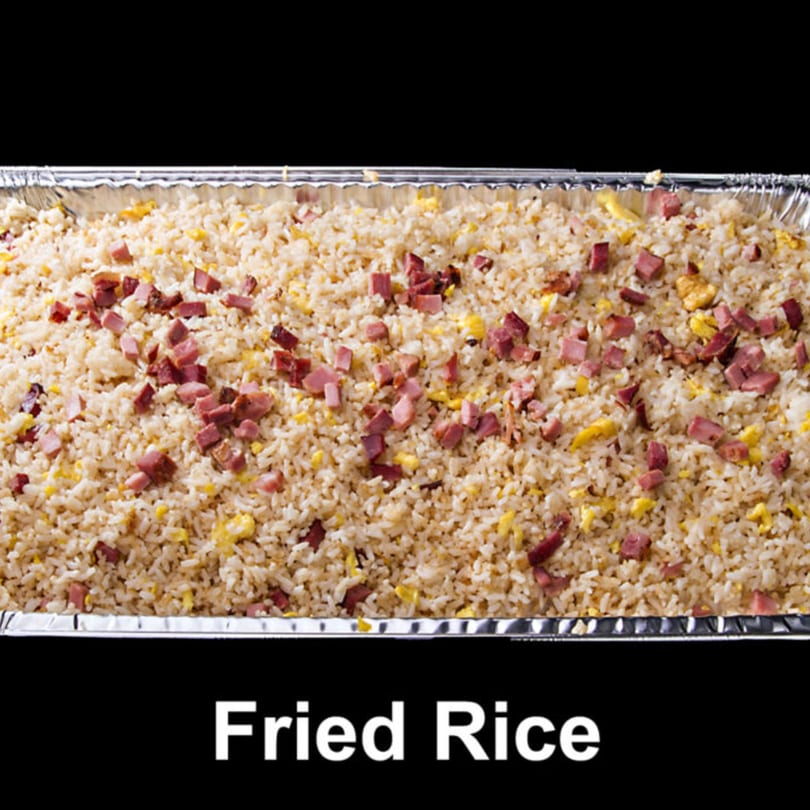 A large aluminum tray filled with fried rice, scrambled eggs, and diced ham.