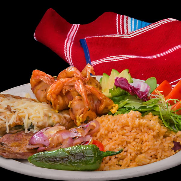 Las Tres Casuelas Tex-Mex plate with bacon-wrapped shrimp, steak, rice, beans, salad, and a pepper.