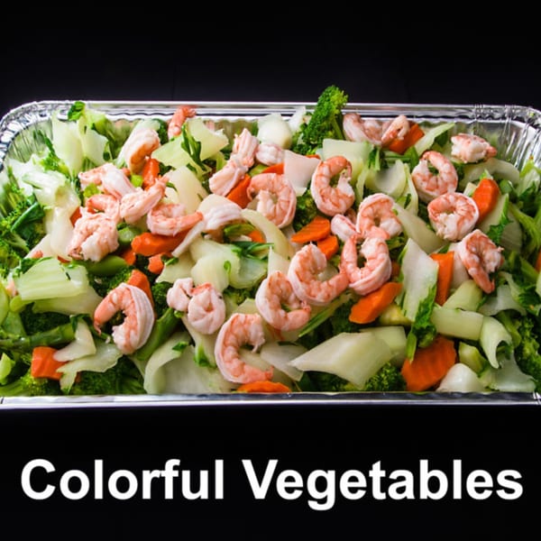 Shrimp and colorful vegetables, including broccoli, carrots, and cabbage, in a foil catering tray.