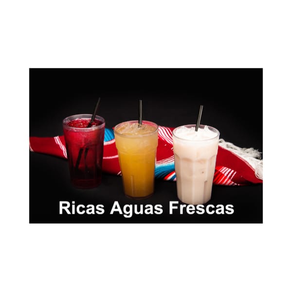 Three colorful aguas frescas in clear cups with straws, on a red and blue striped fabric.